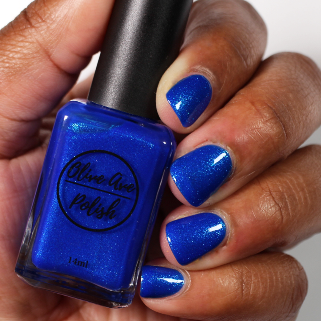 Blue glitter nail polish swatch on medium dark skin tone