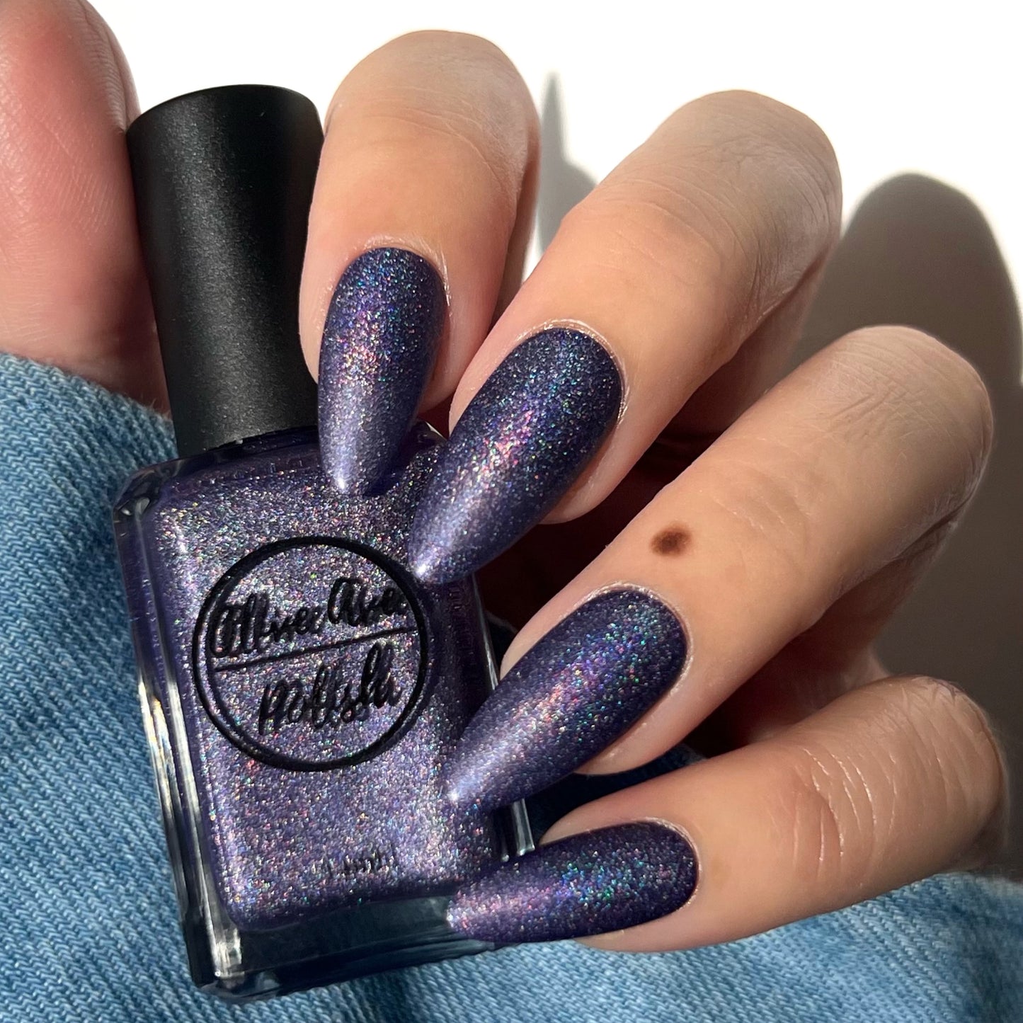 Purple holographic nail polish swatch on pale skin tone