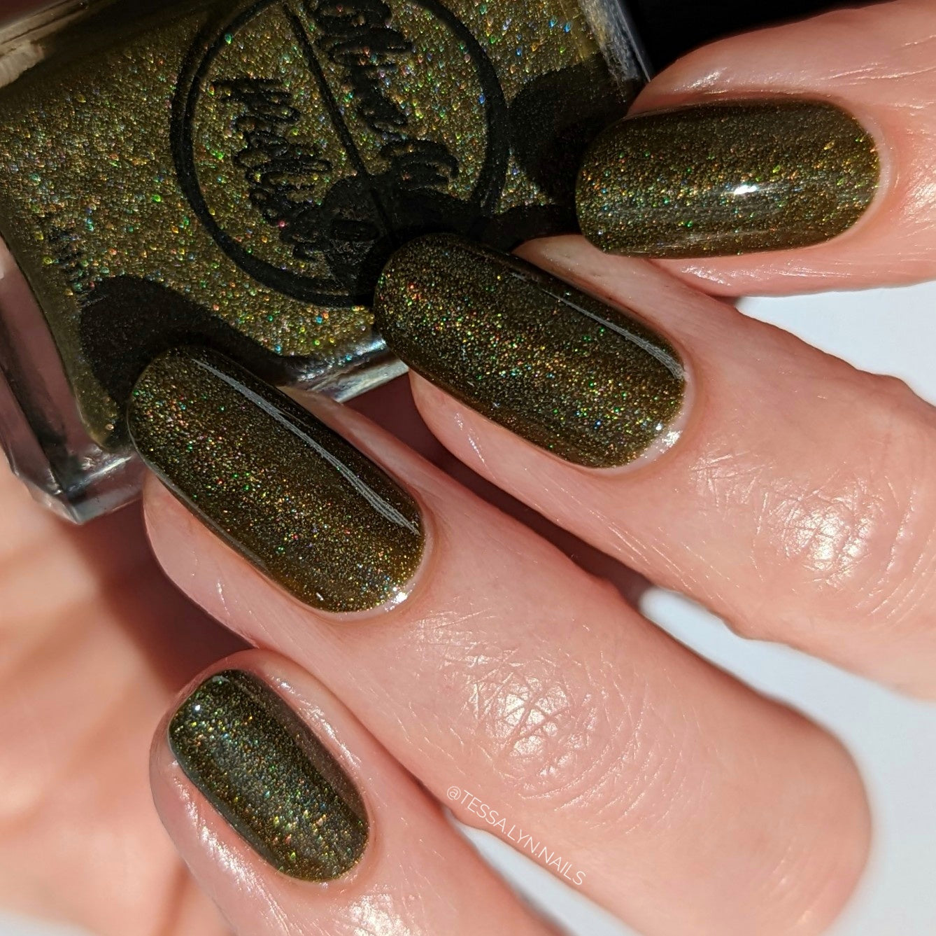 Green holographic nail polish swatch on pale skin tone