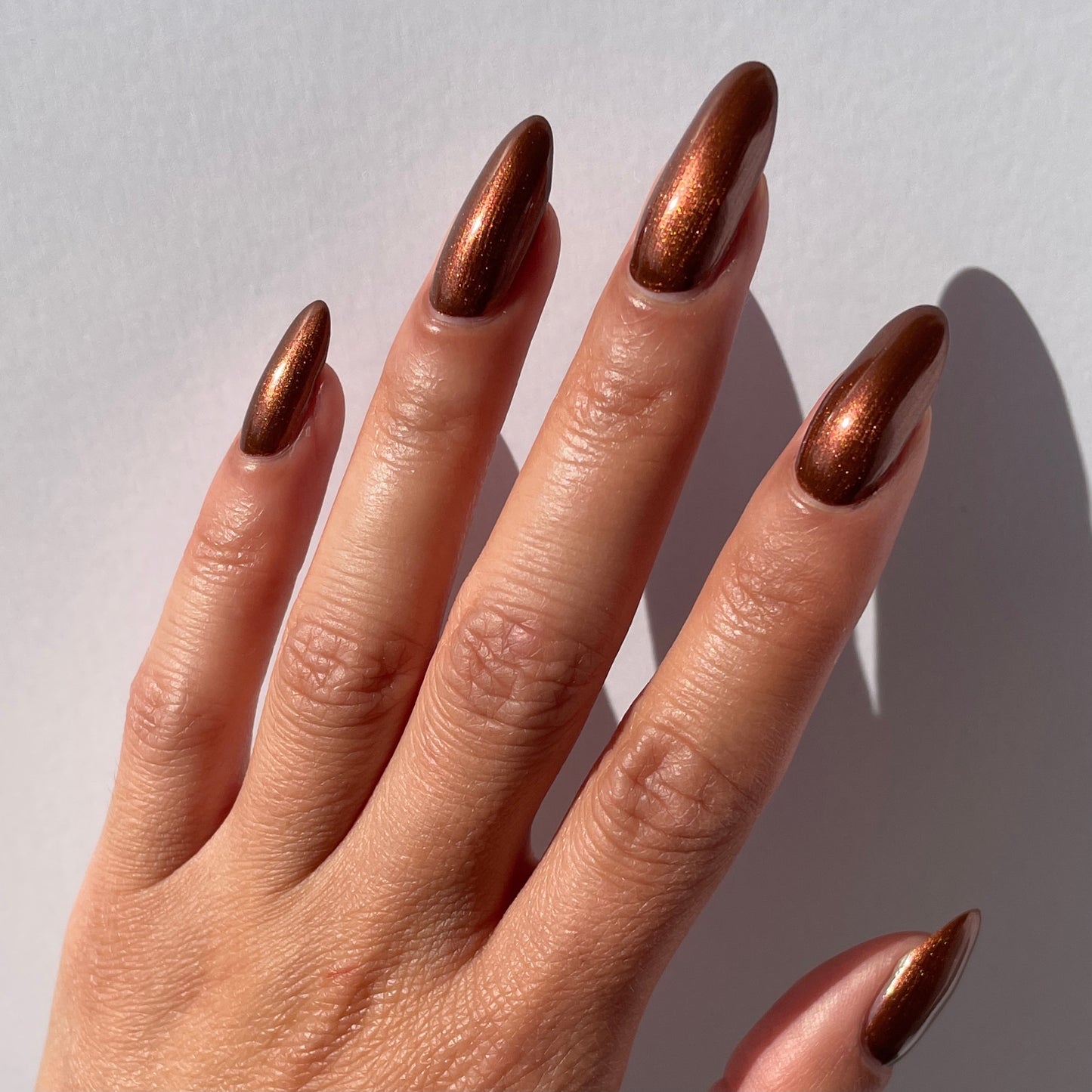 metallic brown nail polish swatch on pale skin tone