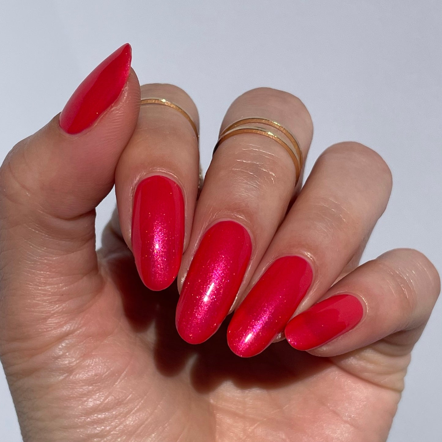 coral shimmer nail polish swatch on medium skin tone