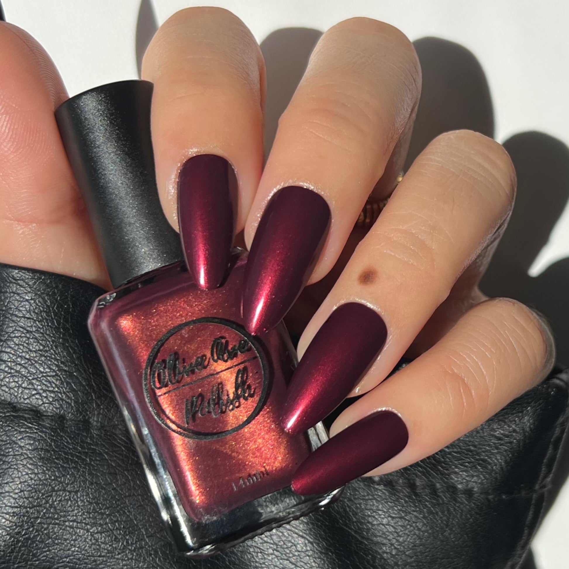 burgundy nail polish with gold shimmer swatch on pale skin tone