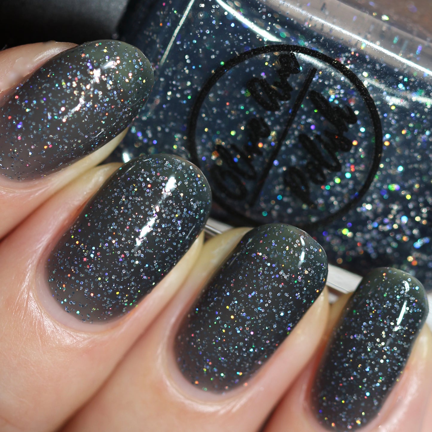 Black holographic nail polish swatch on pale skin tone