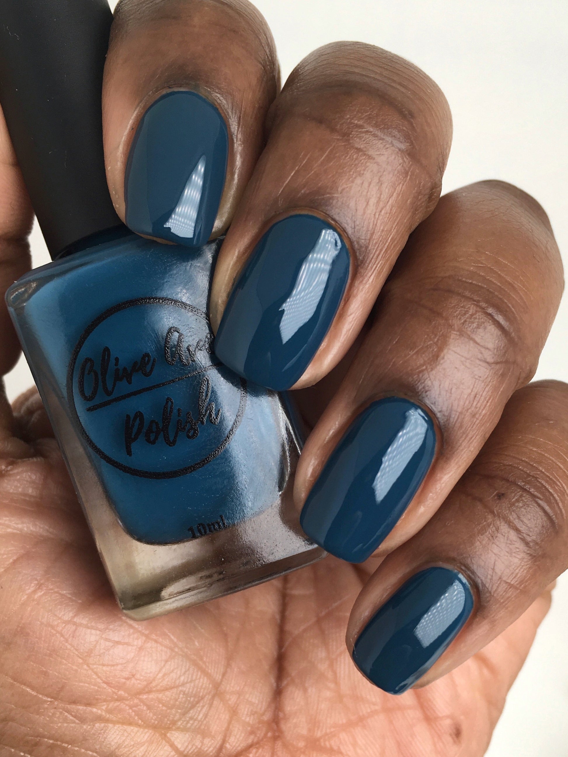 Peacock blue nail polish swatch on medium deep skin tone