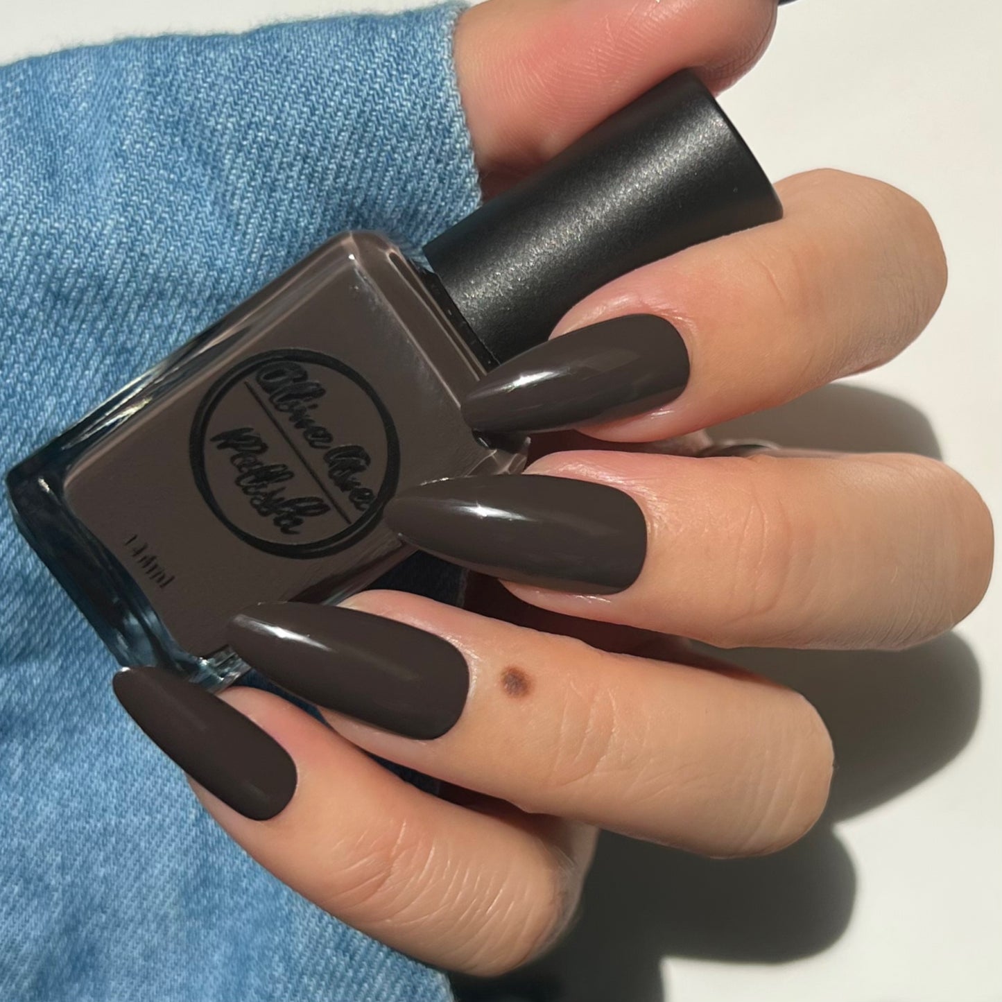 dark brown nail polish swatch on pale skin tone