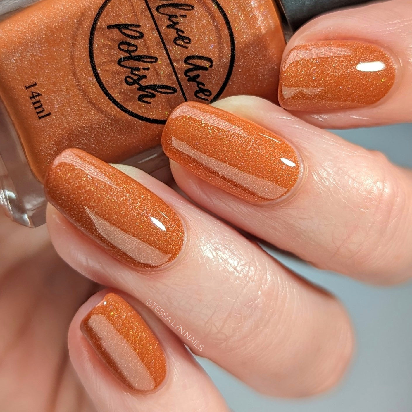 orange holographic nail polish on pale skin tone