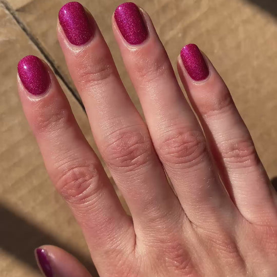 Pink holographic nail polish in sun and indoors