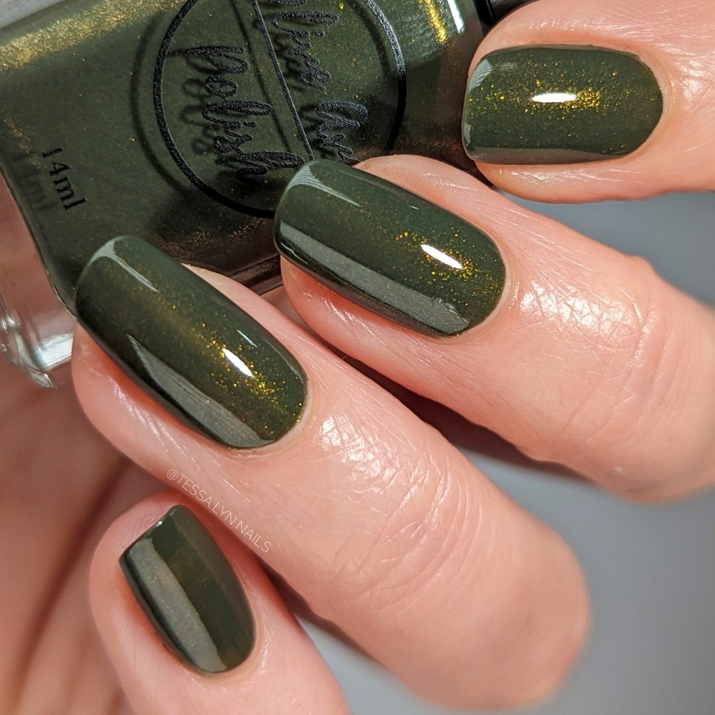 forest green nail polish with gold shimmer on pale skin tone