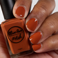 Fall orange nail polish swatch on medium dark skin tone