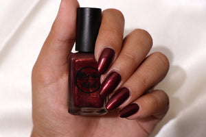 burgundy nail polish with gold shimmer swatch on pale skin tone