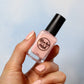 Pink nail polish with gold shimmer swatch on pale skin tone