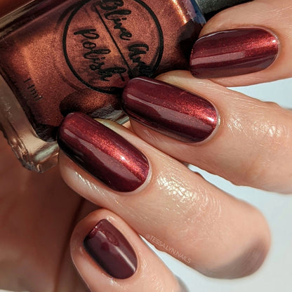 burgundy nail polish with gold shimmer swatch on pale skin tone