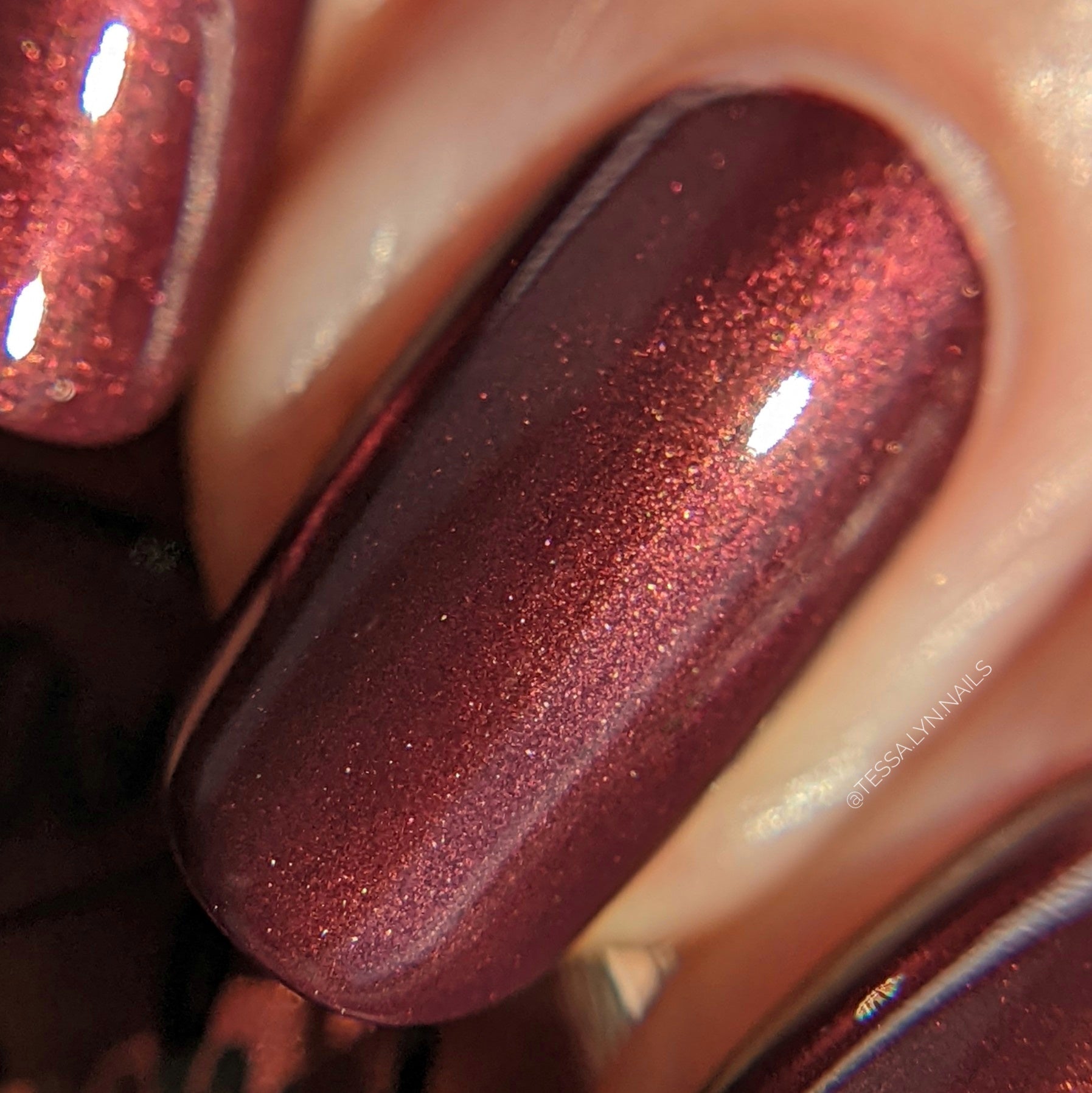 burgundy nail polish with gold shimmer swatch on pale skin tone