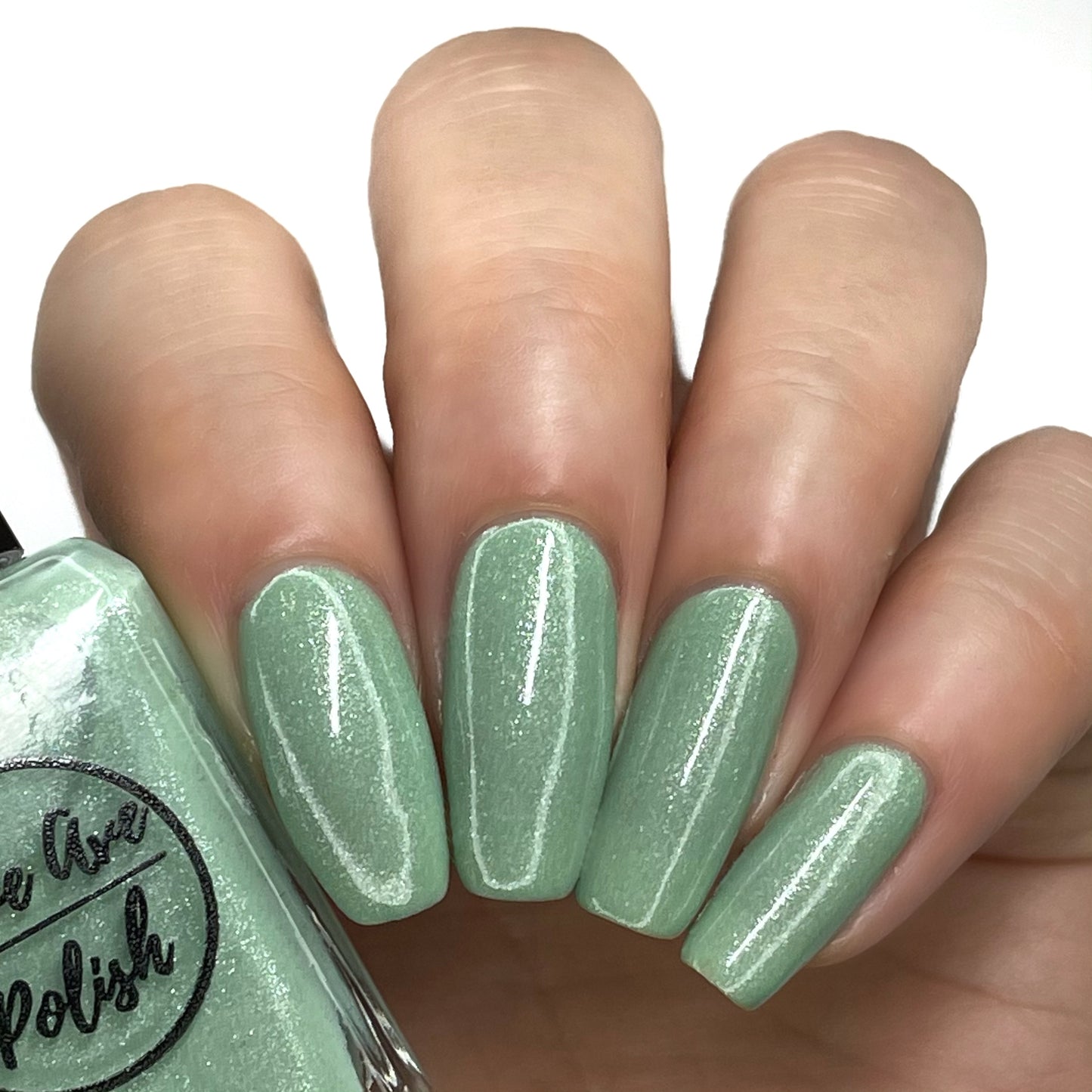 sage green shimmery nail polish swatch on pale skin tone