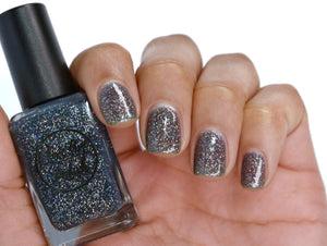 Black holographic nail polish swatch on medium skin tone