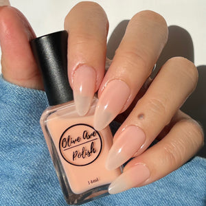 Sheer nude nail polish swatch on pale skin tone
