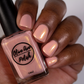 Pink nail polish with gold shimmer swatch on medium dark skin tone