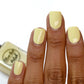 pastel yellow nail polish swatch on medium skin tone