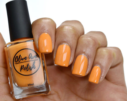 bright orange nail polish swatch on medium skin tone