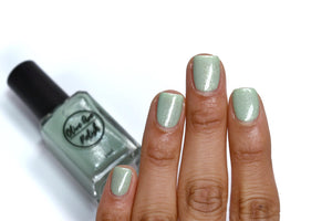 sage green shimmery nail polish swatch on medium skin tone