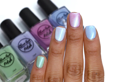 White pearl nail polish swatched on top of green, lavender, pink, blue polishes on medium skin tone
